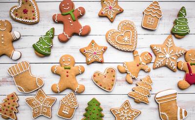 Assorted festive gingerbread cookies with vibrant icing details on a wooden background.