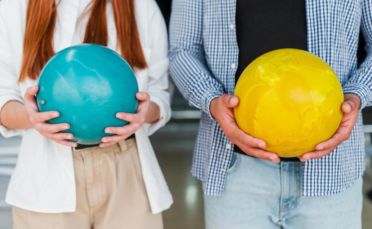 Woman and man holding colorful bowling balls