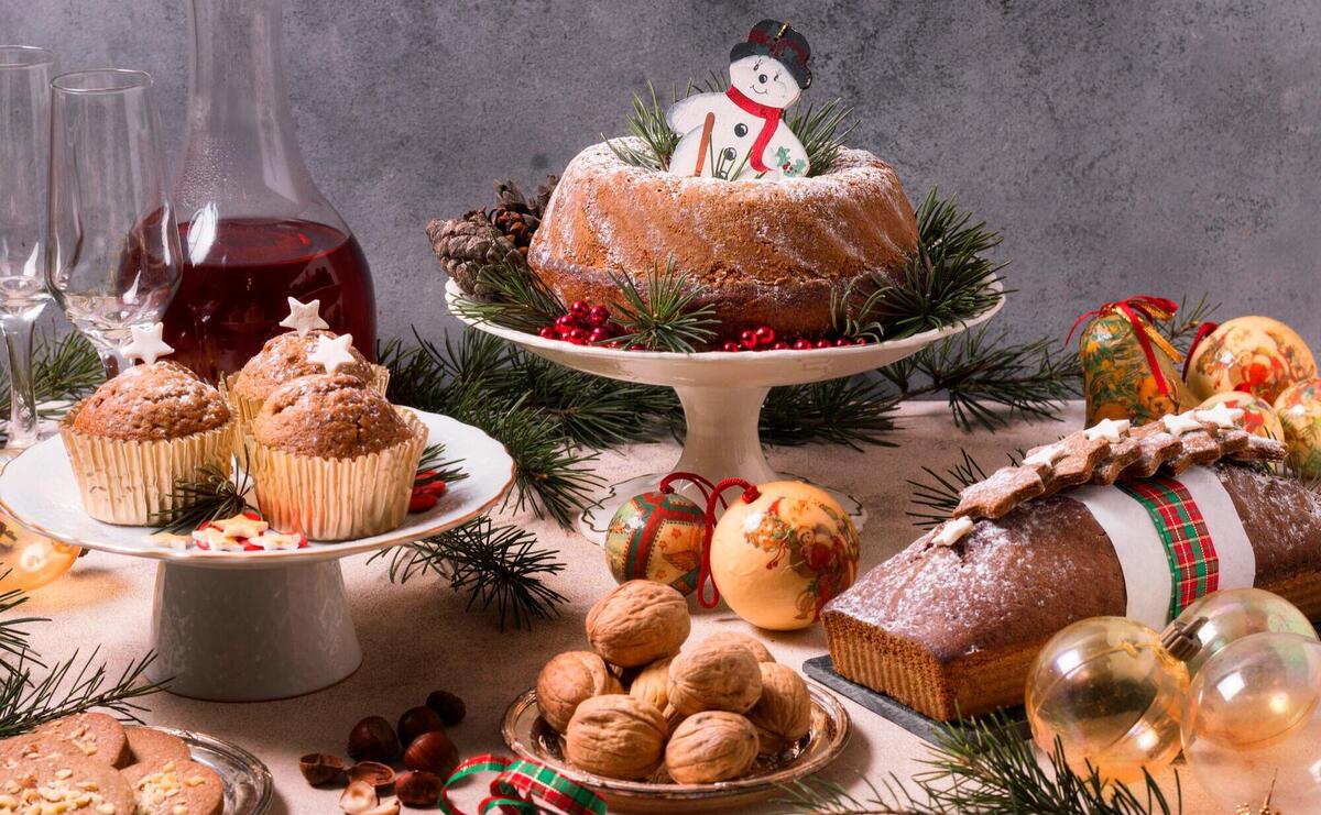 Christmas spread with festive desserts, wine, and ornaments on a rustic backdrop.