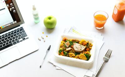 A plate of food next to a laptop.