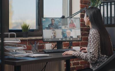 A woman in a virtual meeting with colleagues, illustrating modern remote work dynamics.