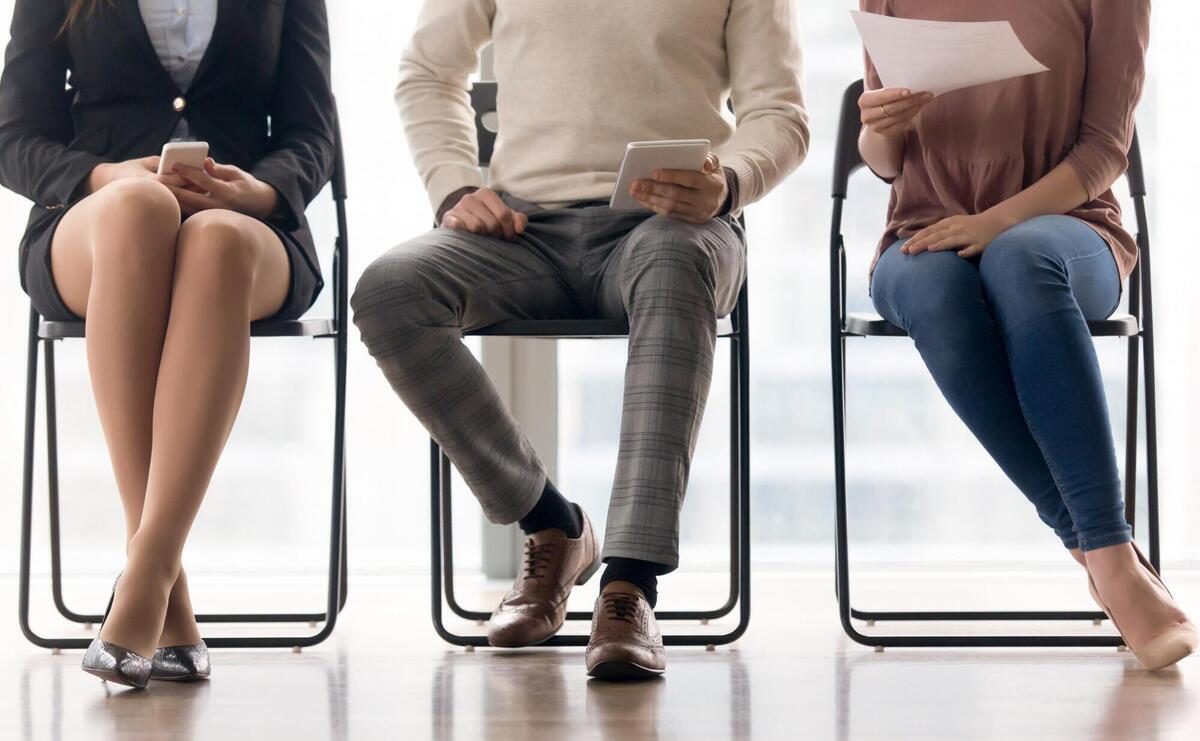 Group of people waiting for job interview, sitting on chairs.