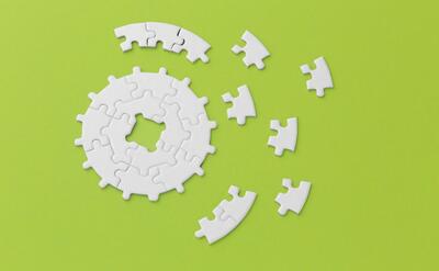White puzzle pieces scattered on a bright green backdrop, symbolizing problem-solving.