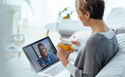 Woman using laptop and having video call with her doctor while sitting at home