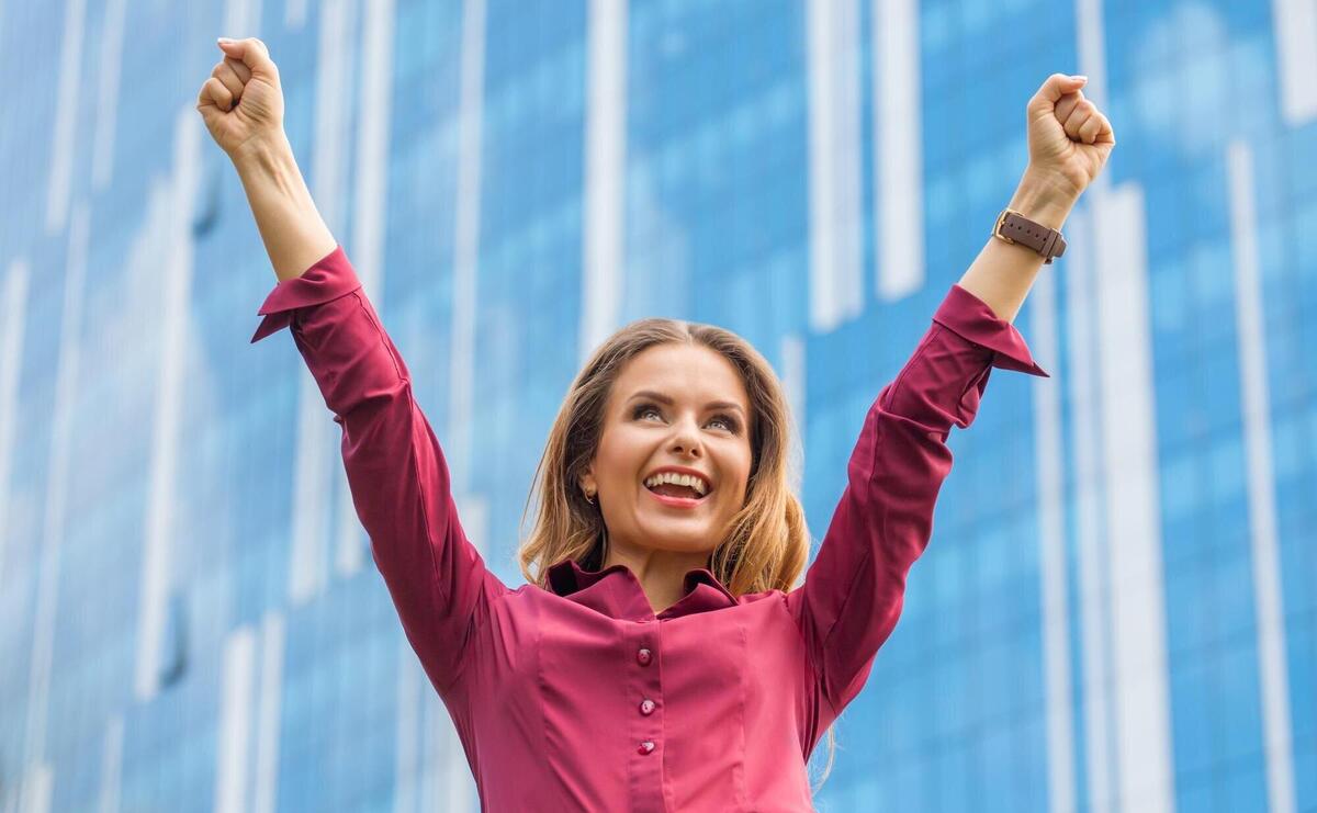 Businesswoman celebrating victory in the city centre. pretty lady smiling with her hand raised in front of her office building.