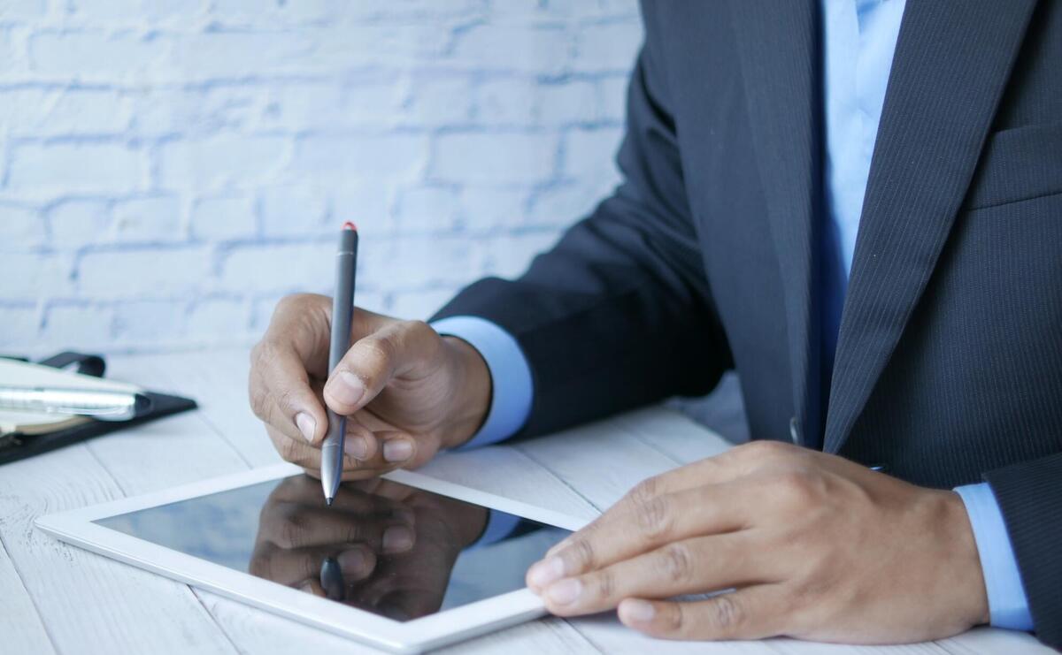 A business man writing on a tablet.