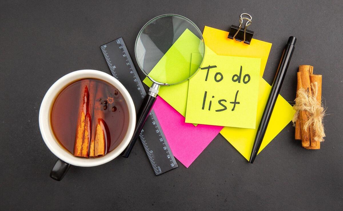 Top view to do list written on yellow sticky note colorful sticky notes lupa pen cinnamon sticks ruler cup of tea