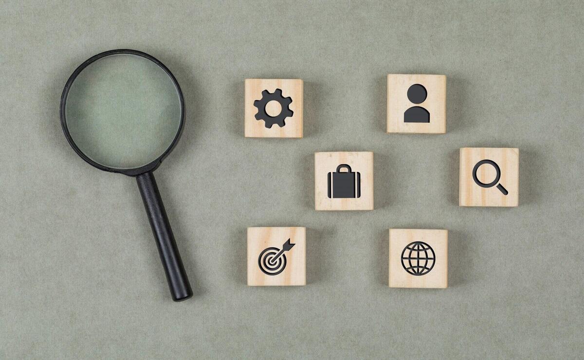 Financial concept with wooden cubes, magnifying glass on grey background flat lay.